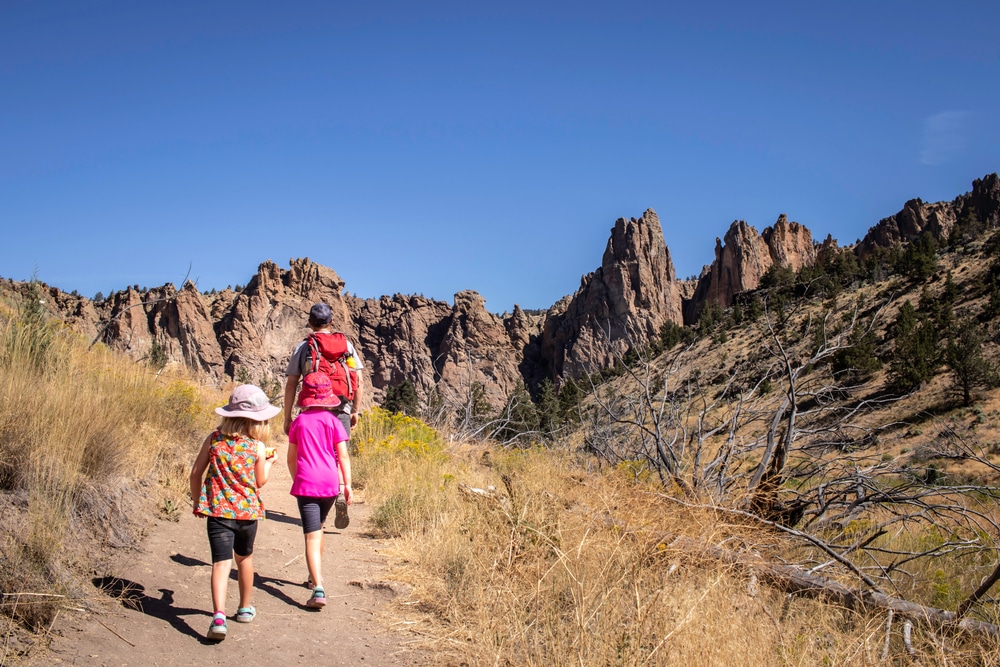 A Dad and his kids hiking at Smith Rock State Park during their family vacation in Oregon.